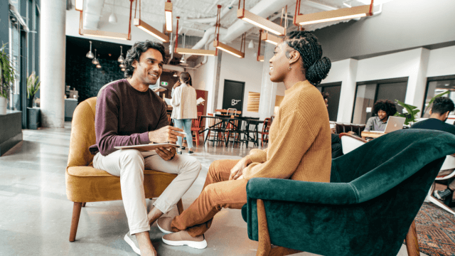 two coworkers talking in office lounge area using most useful languages